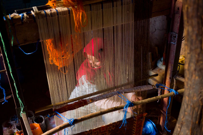 A woman weaving a carpet